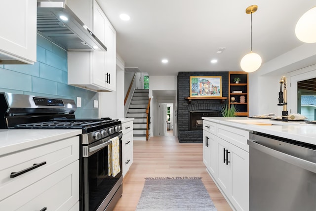 886 Friendly Cir, Charleston, SC 29414 - kitchen with appliances with stainless steel finishes, wall chimney range hood, a fireplace, white cabinetry, and light countertops