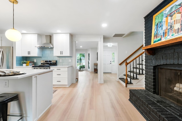 886 Friendly Cir, Charleston, SC 29414 - kitchen with wall chimney range hood, appliances with stainless steel finishes, light countertops, a brick fireplace, and white cabinets