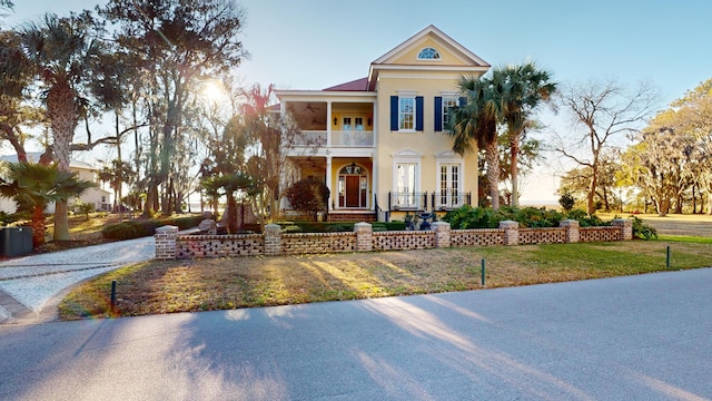 neoclassical home featuring a lawn and a balcony