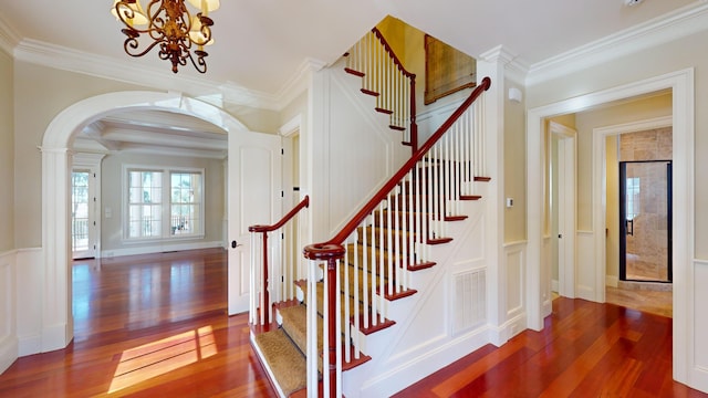 staircase featuring ornamental molding, a chandelier, and hardwood / wood-style floors