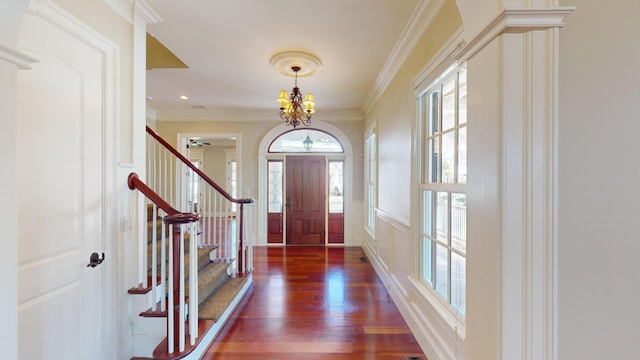 foyer entrance featuring ornamental molding, dark wood-type flooring, and a notable chandelier