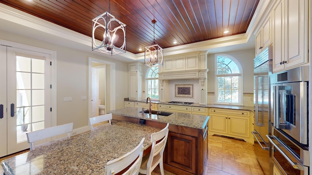 kitchen with cream cabinets, sink, wooden ceiling, and a tray ceiling