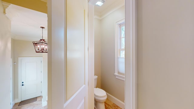 bathroom with an inviting chandelier, ornamental molding, and toilet