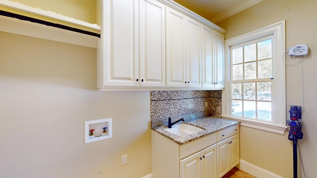 washroom featuring crown molding, sink, hookup for a washing machine, and cabinets