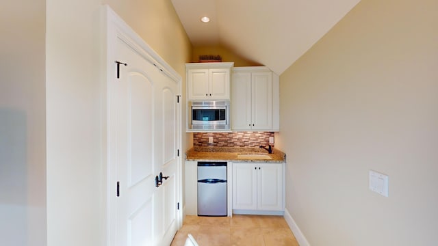 kitchen with sink, refrigerator, stainless steel microwave, light stone countertops, and white cabinets