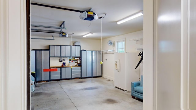 garage with a garage door opener and white fridge with ice dispenser