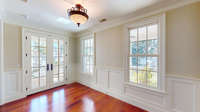 entryway with wood-type flooring, ornamental molding, and french doors