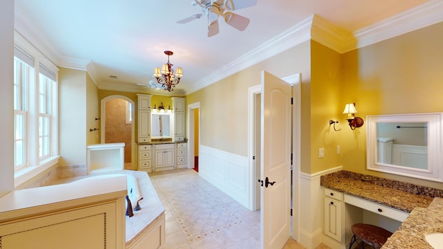 bathroom with ornamental molding, ceiling fan with notable chandelier, and vanity