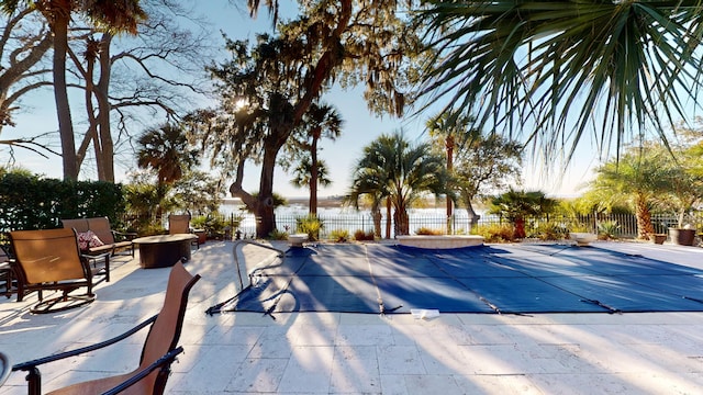 view of pool with a fire pit, a patio, and a water view