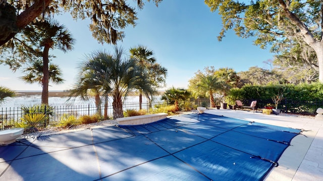 view of swimming pool featuring a water view and a patio