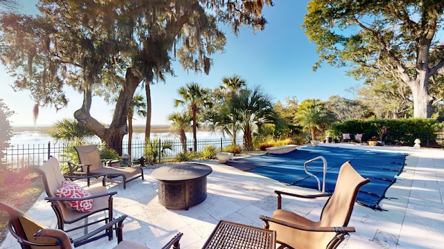 view of pool featuring a water view, an outdoor fire pit, and a patio area