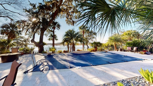 view of pool featuring a water view and a patio