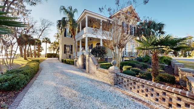 view of front of house featuring ceiling fan and a balcony