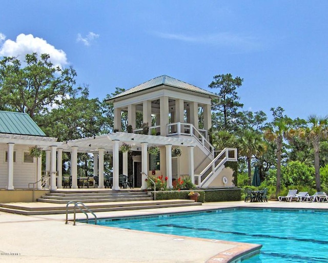 rear view of property featuring a community pool, a pergola, and a patio area