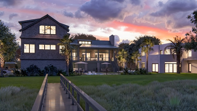 27 Rebellion Rd, Charleston, SC 29407 - back of property at dusk with a lawn, a standing seam roof, a chimney, and metal roof