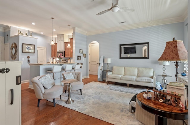 living room featuring light wood-type flooring, crown molding, and ceiling fan