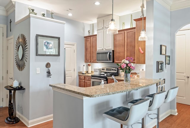 kitchen featuring a kitchen breakfast bar, light hardwood / wood-style floors, light stone counters, kitchen peninsula, and stainless steel appliances