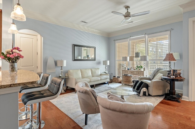 living room featuring ceiling fan, hardwood / wood-style flooring, and crown molding