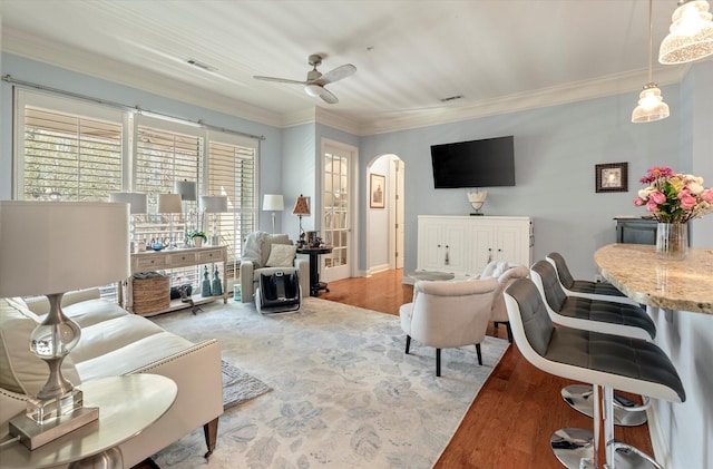 living room featuring ornamental molding, wood-type flooring, and ceiling fan