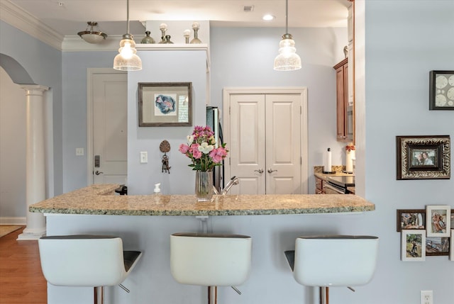 kitchen with decorative light fixtures, hardwood / wood-style floors, kitchen peninsula, and a breakfast bar