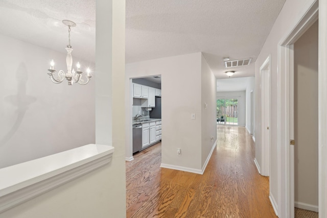 1505 Blaze Ln, Charleston, SC 29412 - hall featuring light wood finished floors, a chandelier, and a textured ceiling