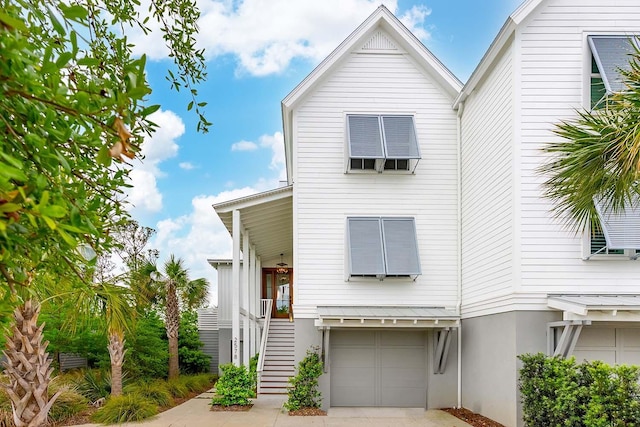 view of front of house with stairway, an attached garage, and driveway