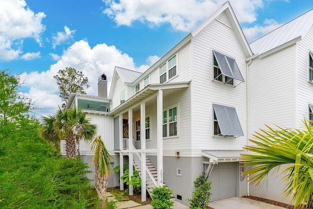 view of side of property featuring an attached garage, driveway, stairway, and metal roof