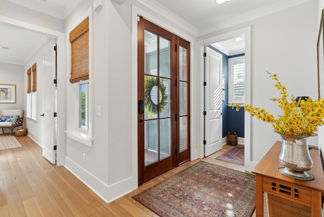 foyer featuring crown molding, light wood finished floors, and a wealth of natural light