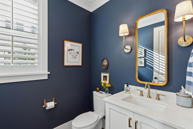 half bath with vanity, ornamental molding, and toilet