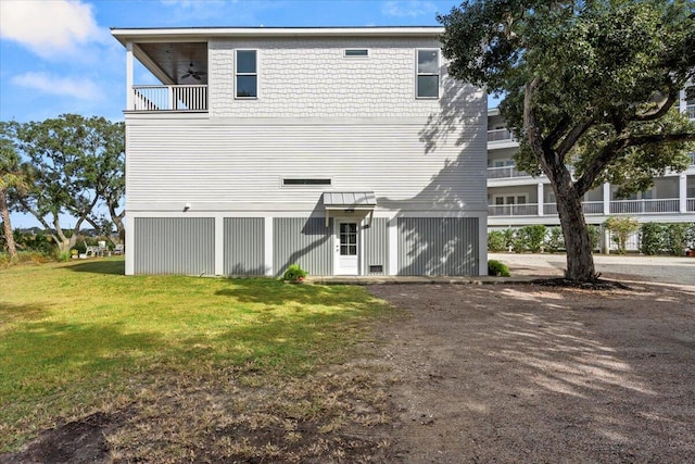 back of property featuring a balcony and a yard