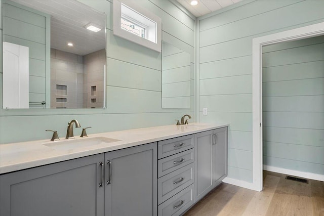 bathroom featuring hardwood / wood-style floors, vanity, and wooden walls