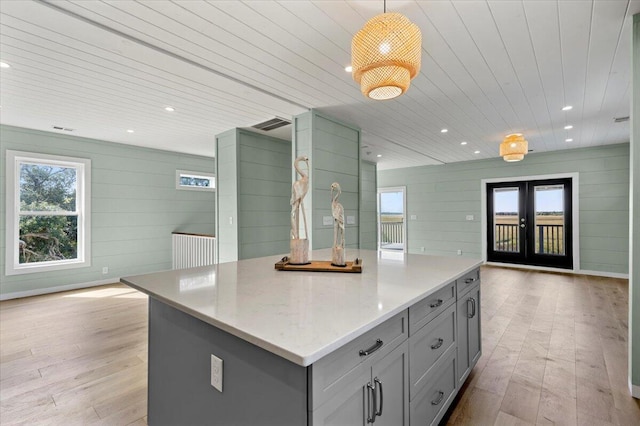 kitchen with pendant lighting, plenty of natural light, a kitchen island, and light hardwood / wood-style flooring