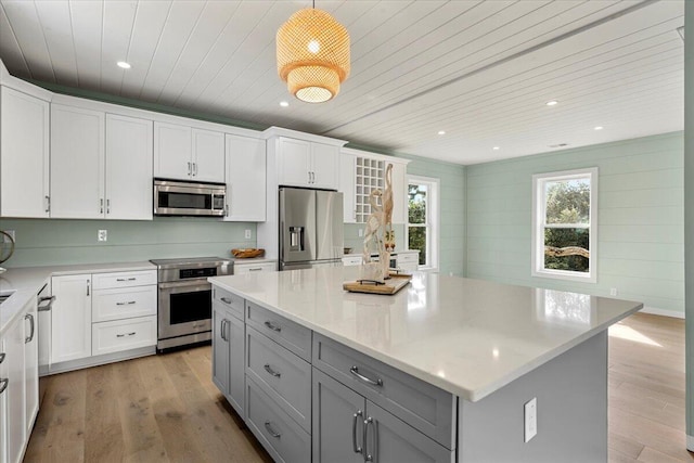 kitchen with white cabinetry, gray cabinetry, appliances with stainless steel finishes, and a center island