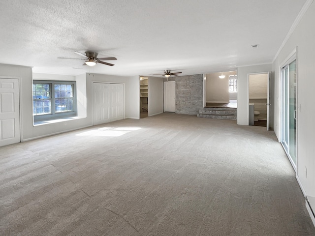 unfurnished living room featuring carpet, a textured ceiling, ceiling fan, and crown molding