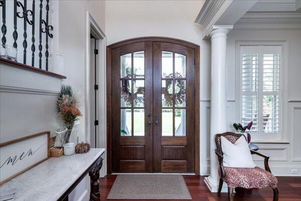 entrance foyer with dark wood finished floors, crown molding, healthy amount of natural light, french doors, and a decorative wall