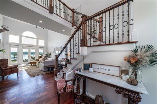 stairway with a high ceiling, wood finished floors, and recessed lighting