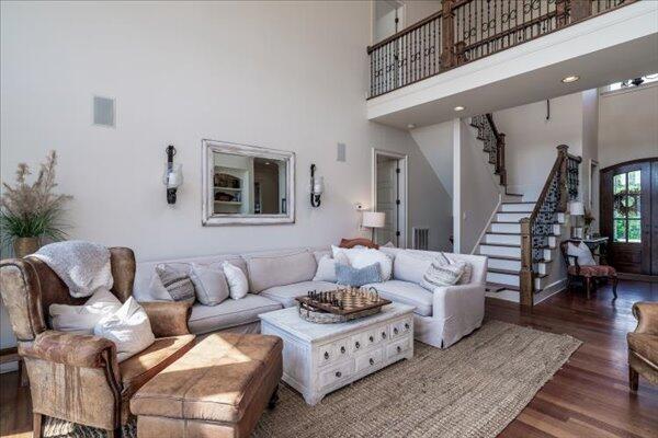 living room with a towering ceiling, wood finished floors, and stairway