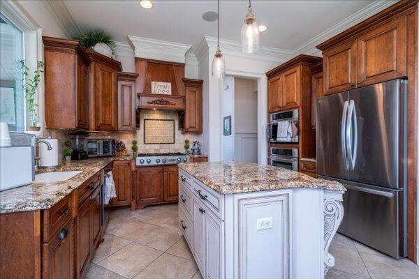 kitchen featuring stainless steel appliances, light stone counters, light tile patterned floors, decorative backsplash, and ornamental molding