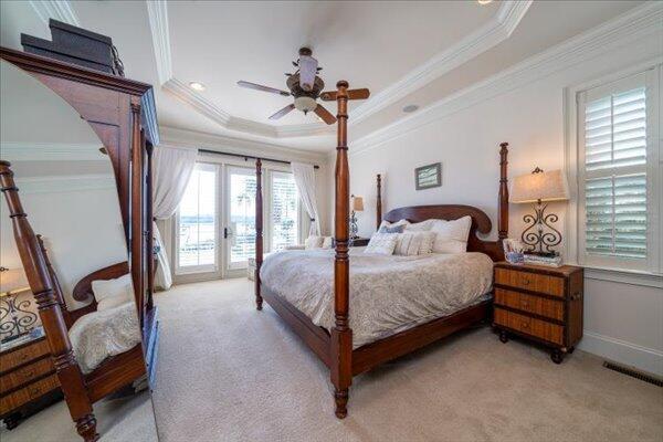 bedroom with light carpet, access to exterior, a tray ceiling, crown molding, and french doors