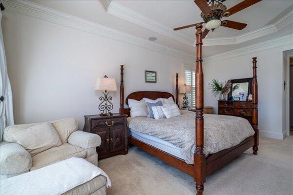 bedroom with crown molding, a raised ceiling, light carpet, and a ceiling fan