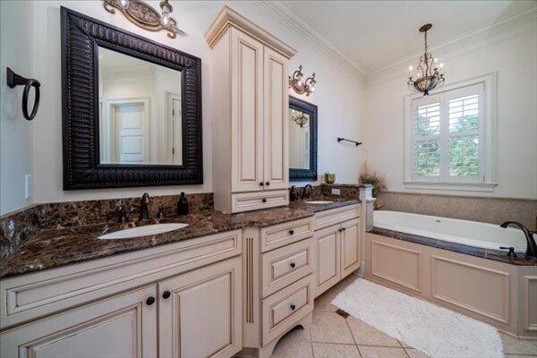 bathroom featuring a chandelier, double vanity, a garden tub, ornamental molding, and tile patterned floors