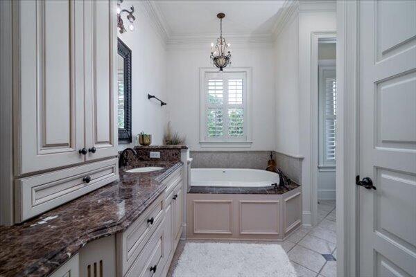 full bathroom featuring a chandelier, a garden tub, vanity, tile patterned floors, and ornamental molding