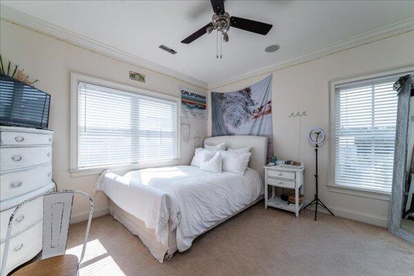 bedroom with crown molding, light carpet, baseboards, and a ceiling fan
