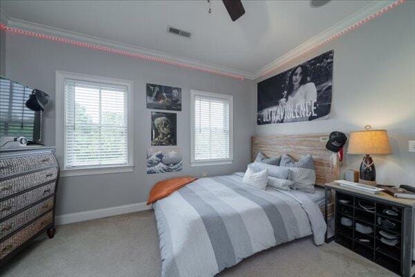 carpeted bedroom with crown molding, baseboards, and a ceiling fan