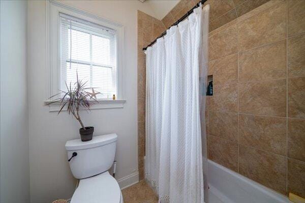 full bathroom featuring toilet and shower / bath combination with curtain