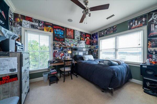 carpeted bedroom with crown molding, baseboards, and a ceiling fan