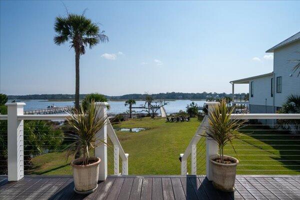 wooden deck with a water view and a lawn