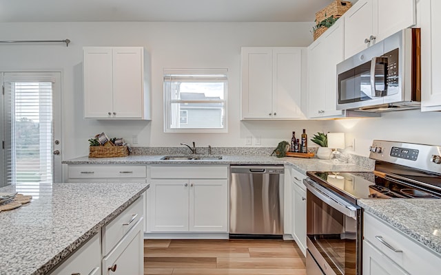 kitchen featuring appliances with stainless steel finishes, light hardwood / wood-style floors, white cabinetry, and sink