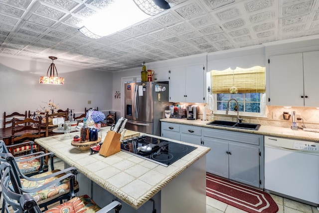 kitchen with an ornate ceiling, a sink, stainless steel fridge, dishwasher, and black electric stovetop