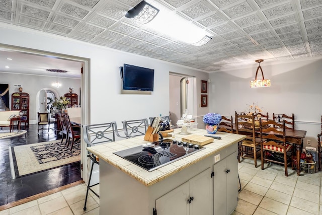 kitchen with an ornate ceiling, tile counters, light tile patterned flooring, arched walkways, and black electric stovetop